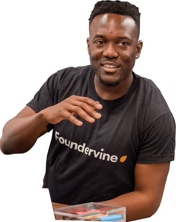 Cecil Adjalo, a Black social entrepreneur smiles in conversation, wearing a black t-shirt branded with the white Foundervine logo.